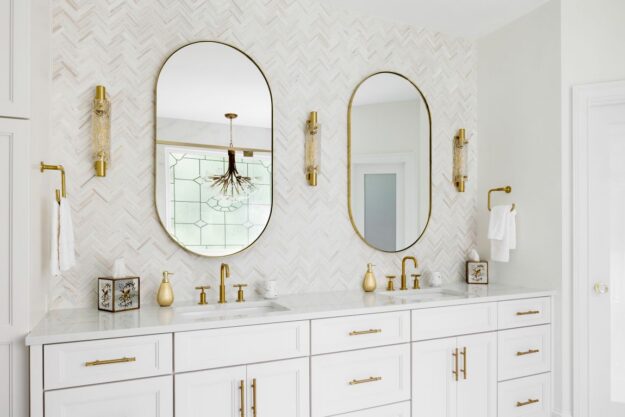 Custom white double vanity with quartz countertop, arched mirrors, and brushed-gold fixtures
