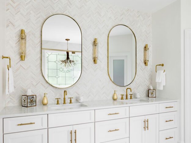 Custom white double vanity with quartz countertop, arched mirrors, and brushed-gold fixtures