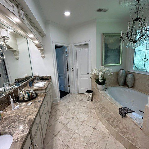 Original Roswell bathroom with long double vanity, built-in jetted tub, and beige tile finishes
